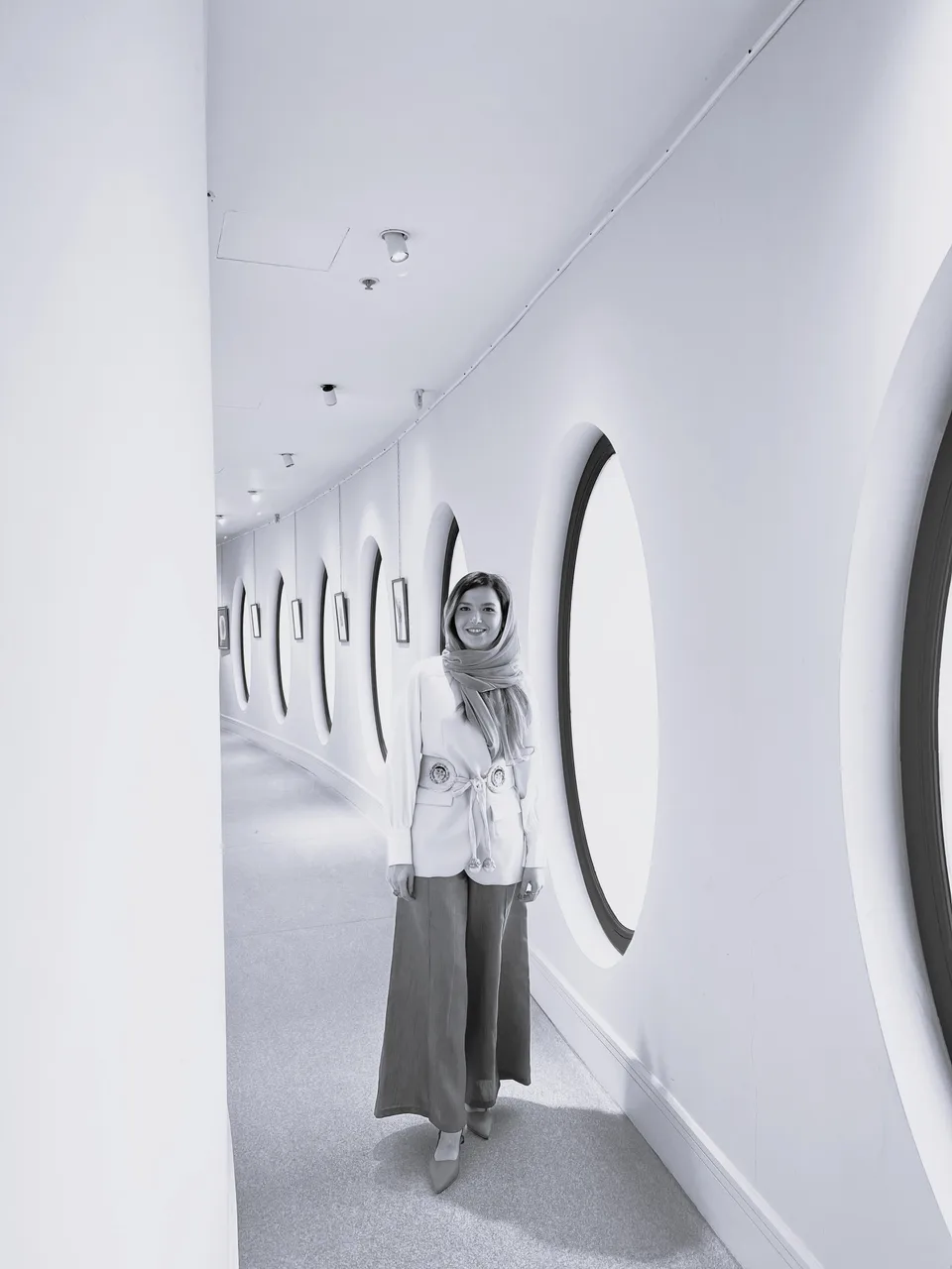 Tina Najafkani standing in a gallery corridor beside arched windows.